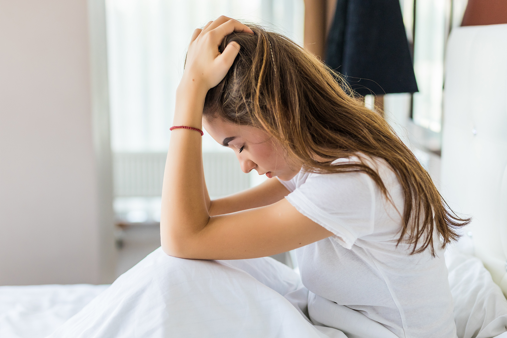 a woman in bed looking frustrated as she isn't getting the bedroom heating right